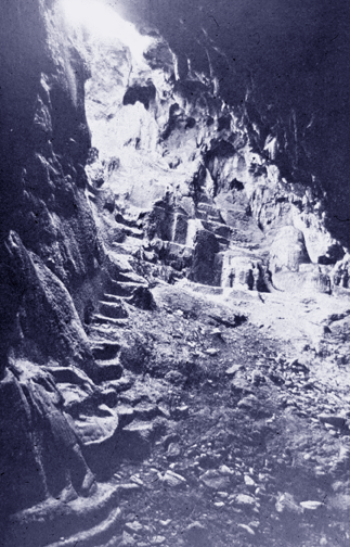 a rocky cavern with cut steps and statue carved out of stone formation